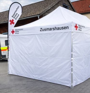 White pop up gazebo 8x4 m with closed side-panels and side-panels with windows. Personalised with the logo of the bavarese red cross.